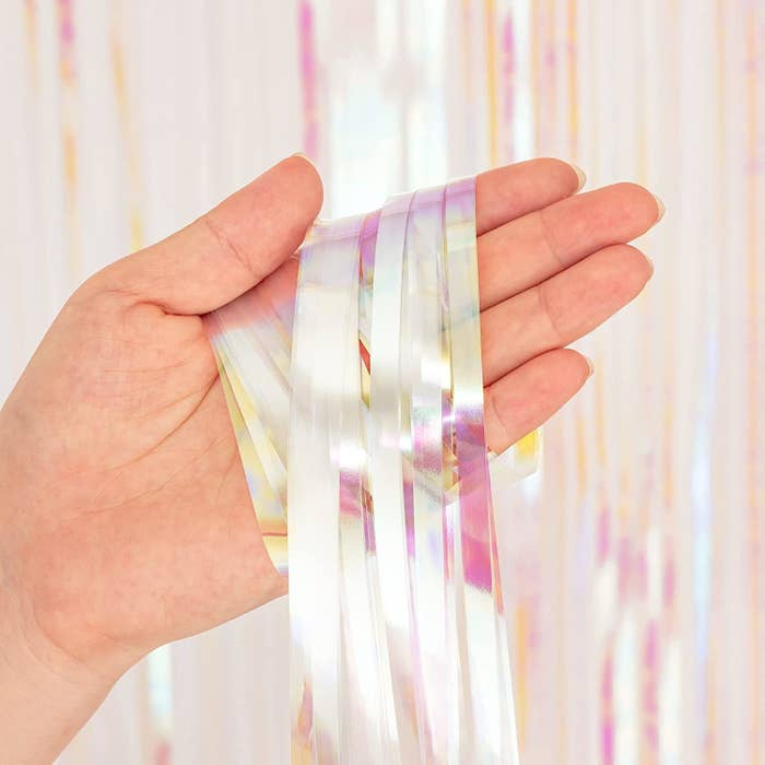 a person holding a part of the fringed foil curtain