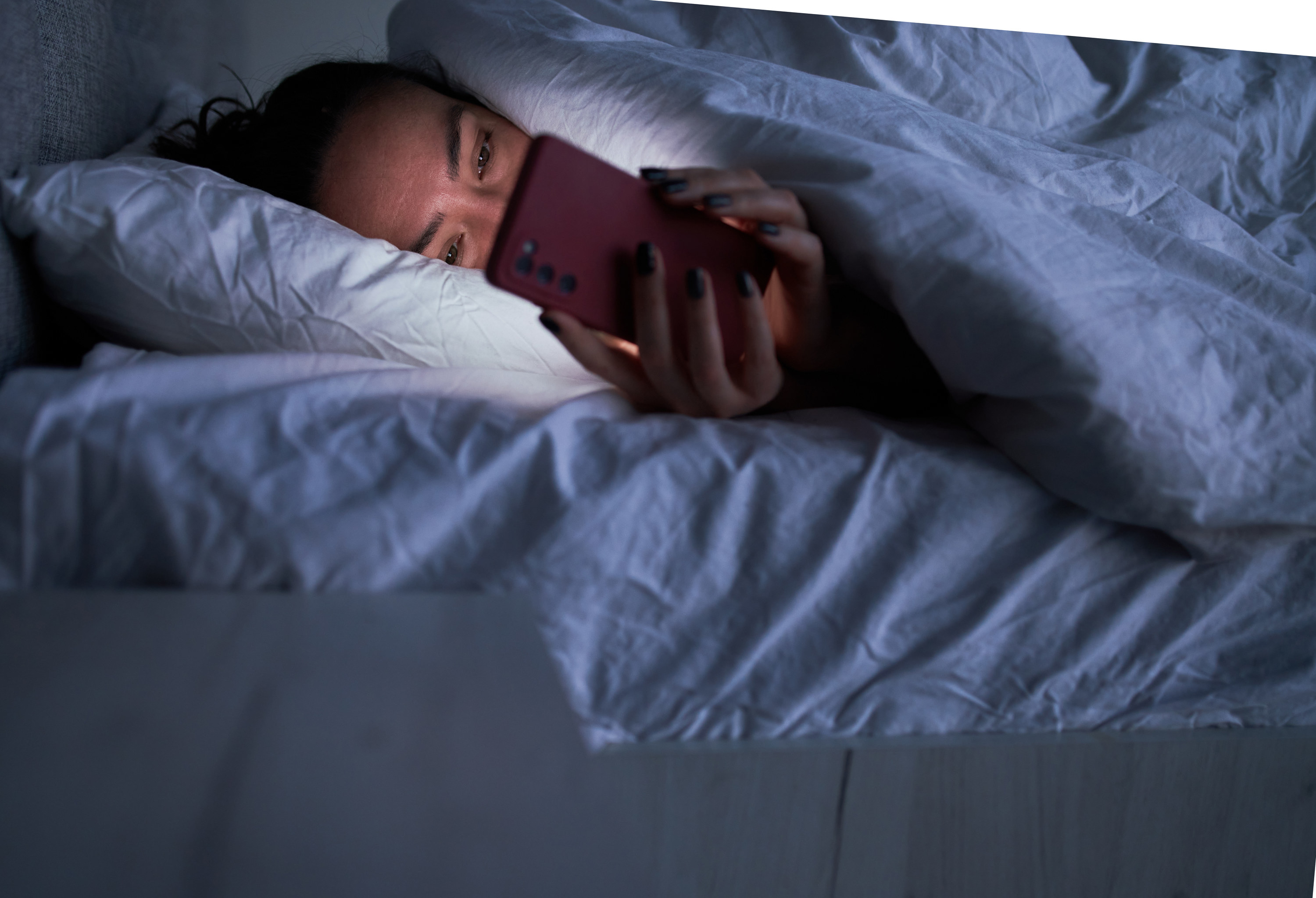 woman scrolling social media on her phone in bed