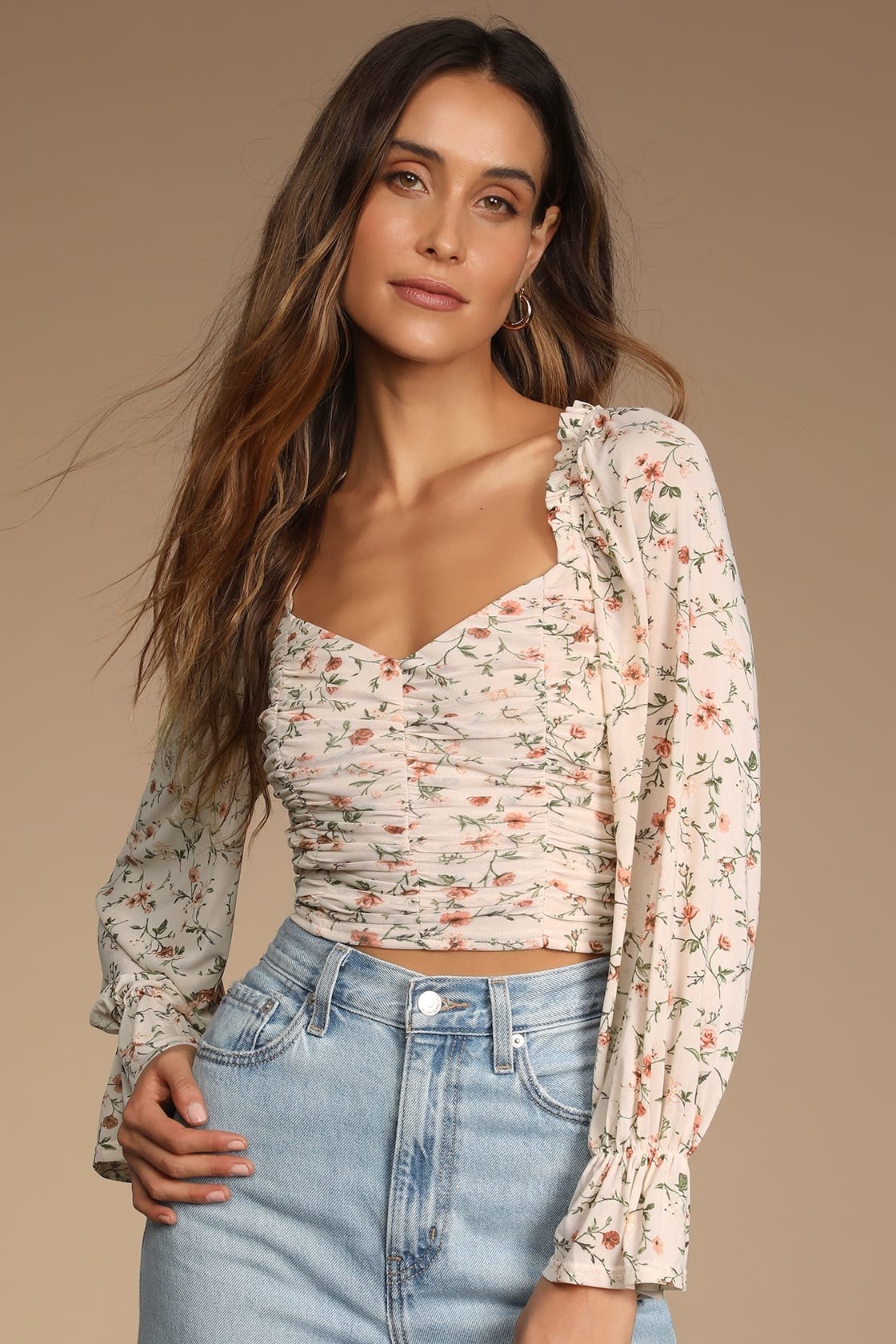 Model wearing floral white blouse with pink and green flowers and jeans