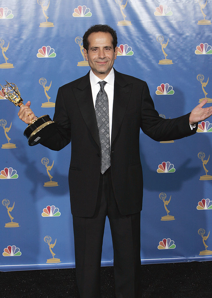On the red carpet in a suit and holding an award