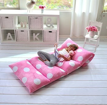 A child model reading a book on the pink polka dot lounger