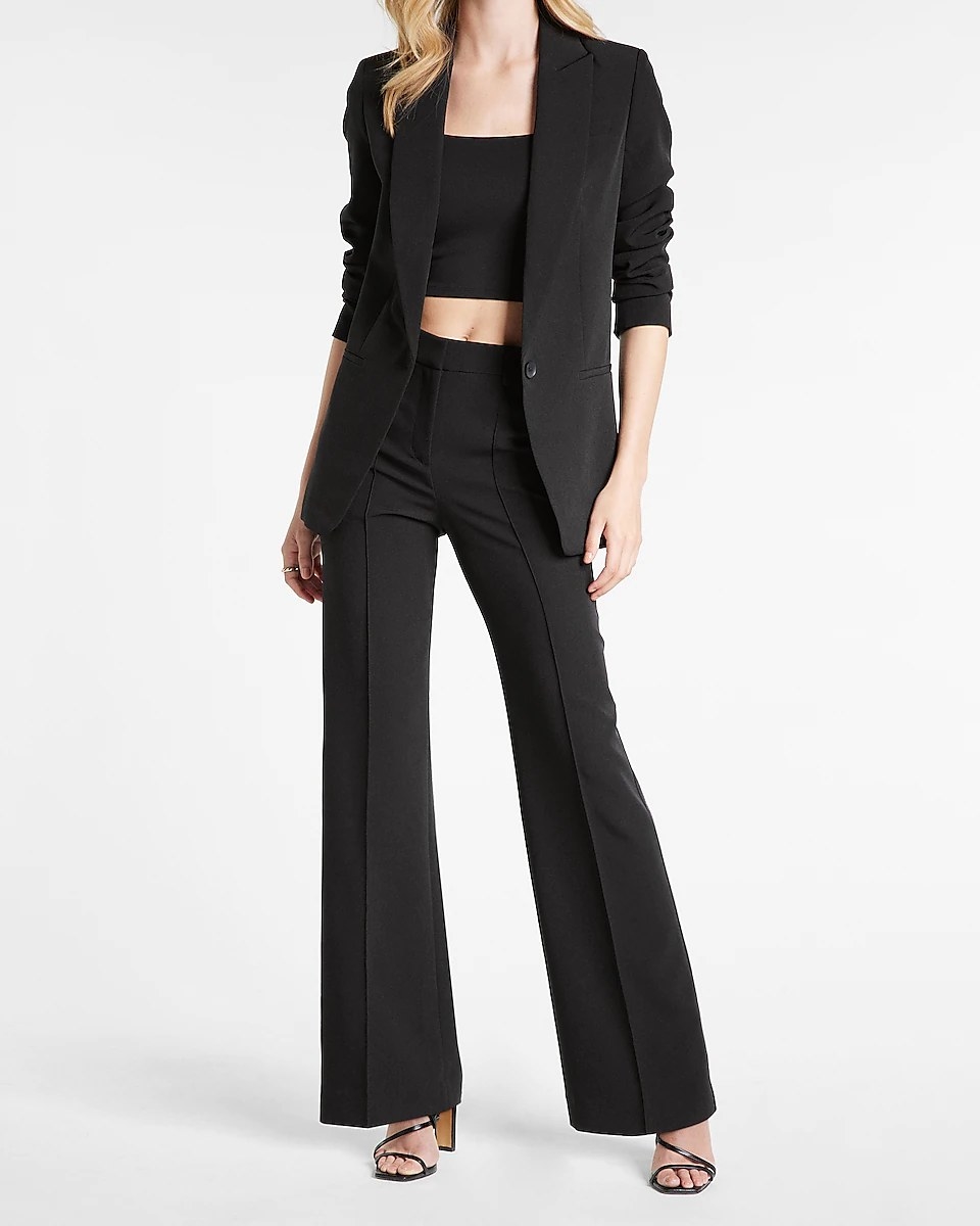 A model wearing the trousers, styled with a black crop top and black oversized blazer