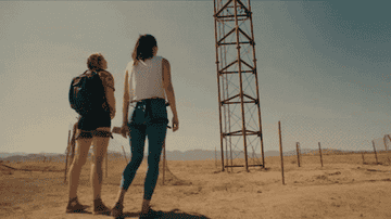 Two women stand at the base of an incredibly tall TV tower.