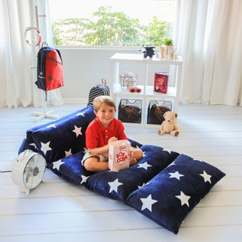 A child model sitting on the blue star print lounge mat