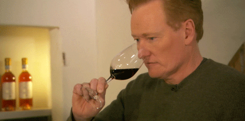 Conan O'Brien sniffing wine in a glass