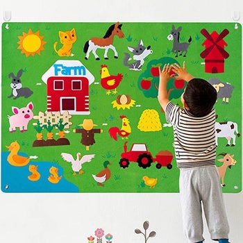 A child model playing with the felt farmhouse