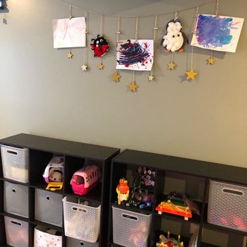 reviewer's photo showing the star garland displaying their kid's art in the playroom