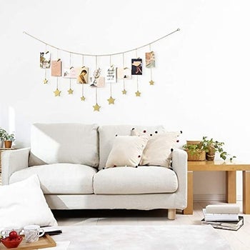 A gold star garland strung above a couch displaying photos