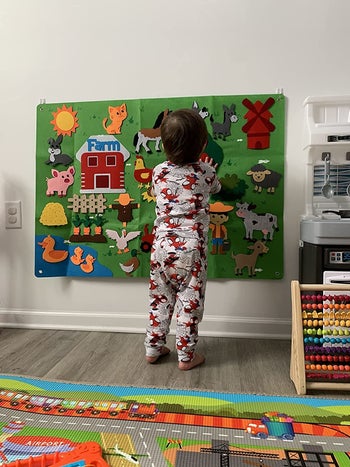 reviewer's child playing with the felt farmhouse wall hanging