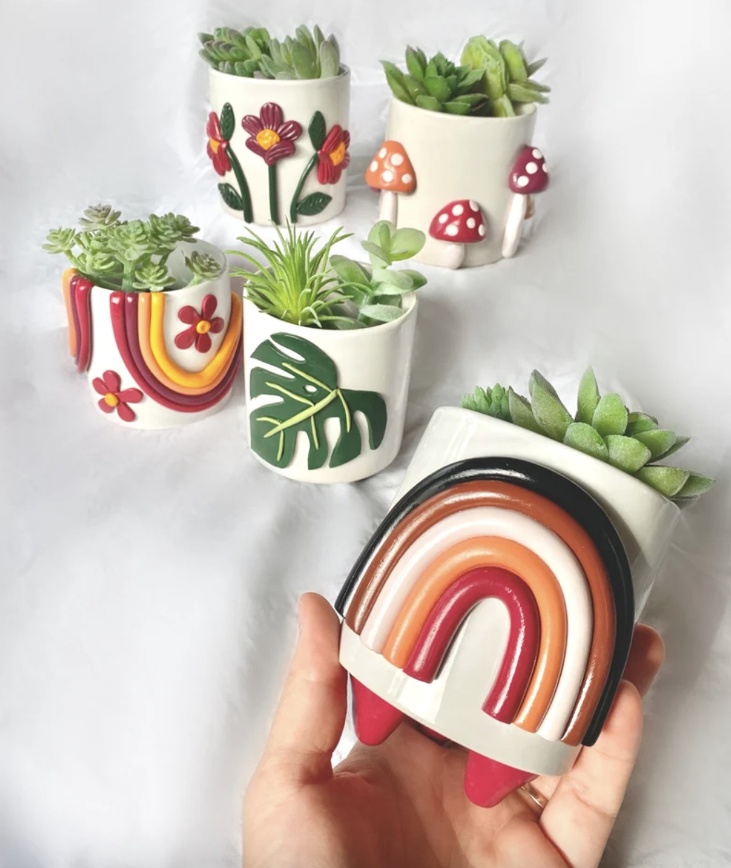 A person holds up one of five handmade planters with cool 3d designs on them