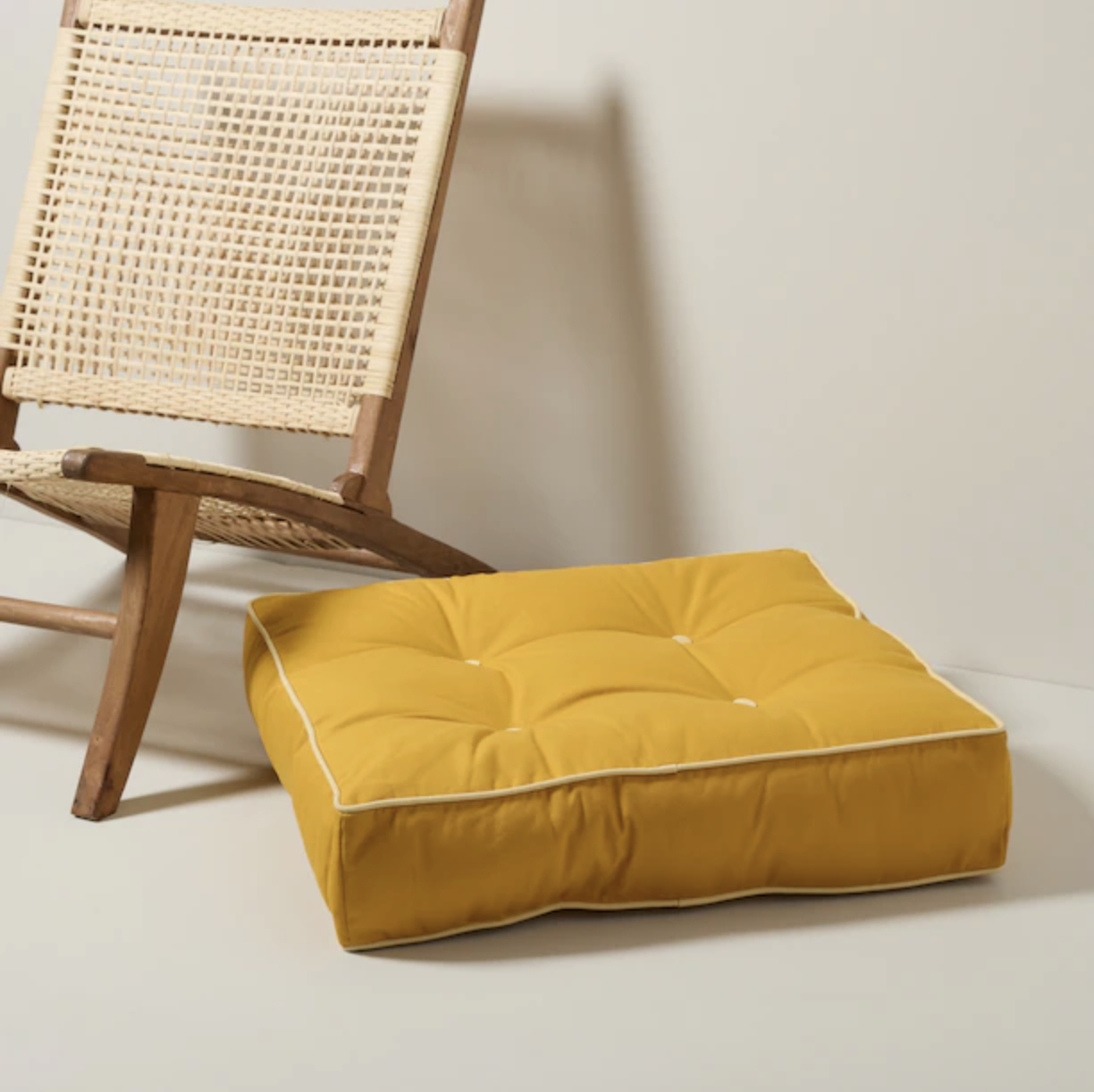 a square tufted pillow next to a cute chair