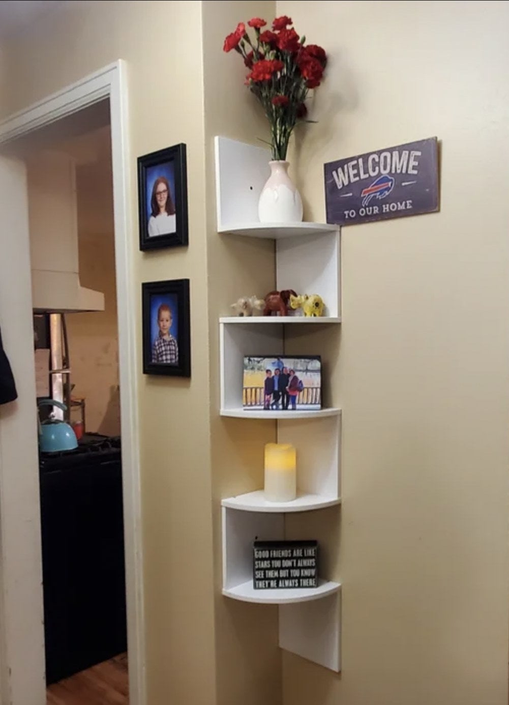 Reviewer&#x27;s home with the white corner shelf displaying candle, framed photo and other decor in corner groove of wall