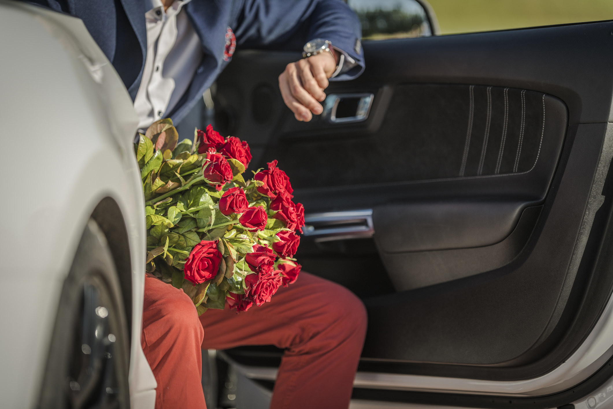 A man with flowers getting out of a car