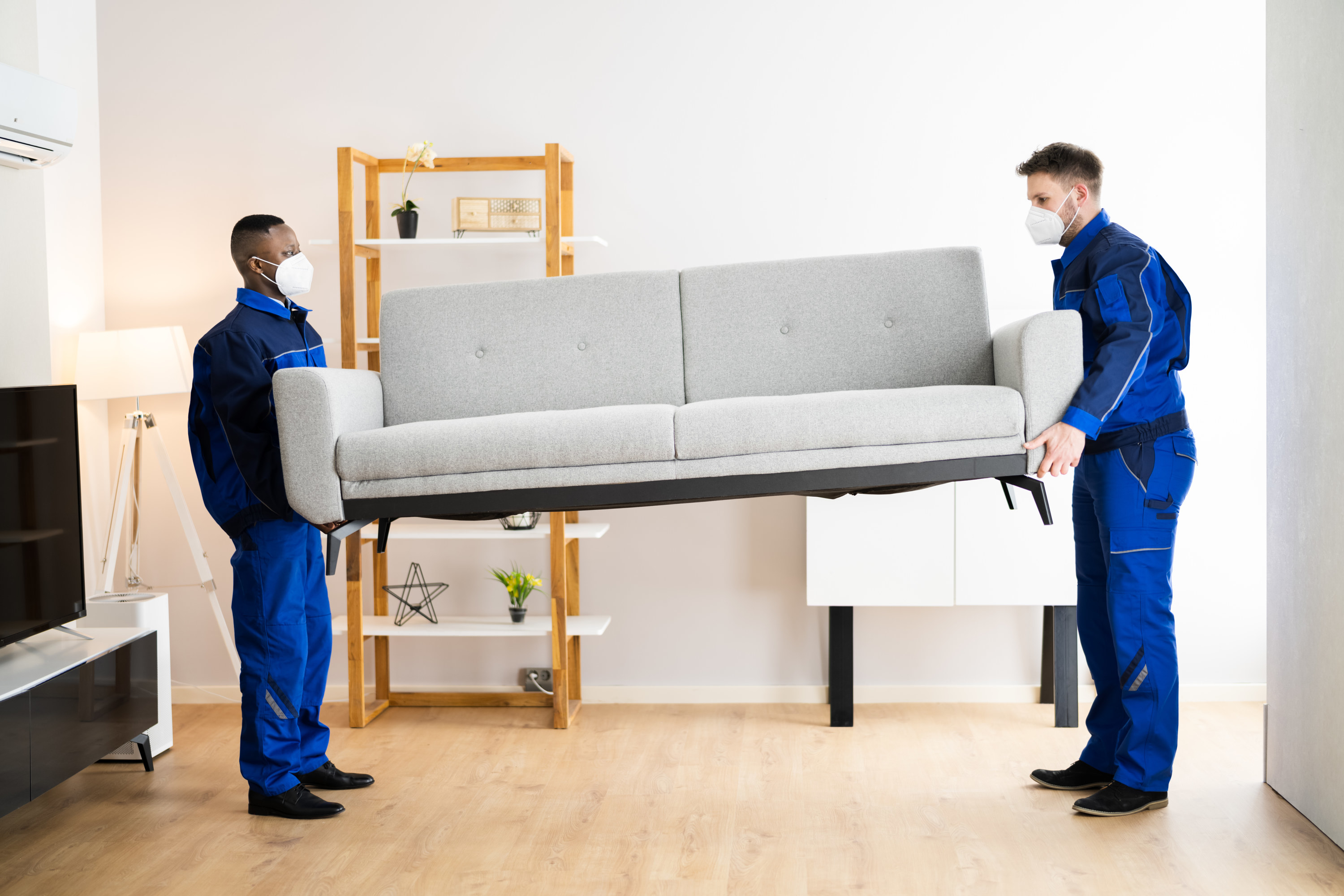 furniture movers lifting a couch wearing face masks