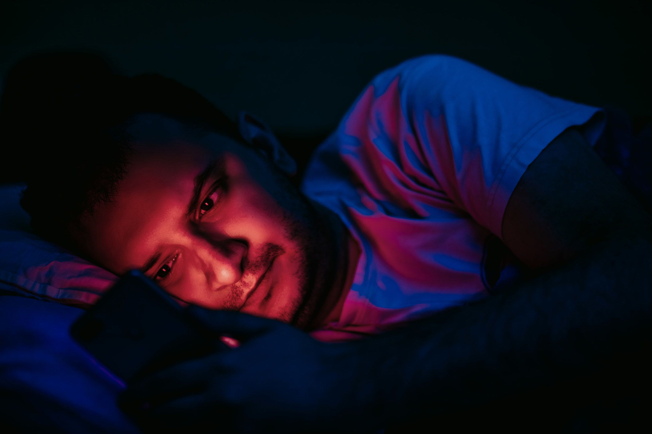 A man on his phone in bed