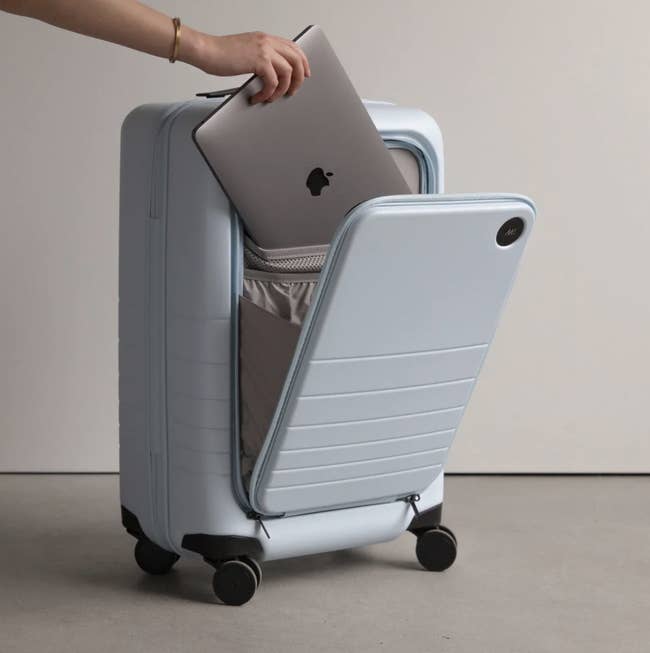 Model placing laptop in Monos carry-on suitcase