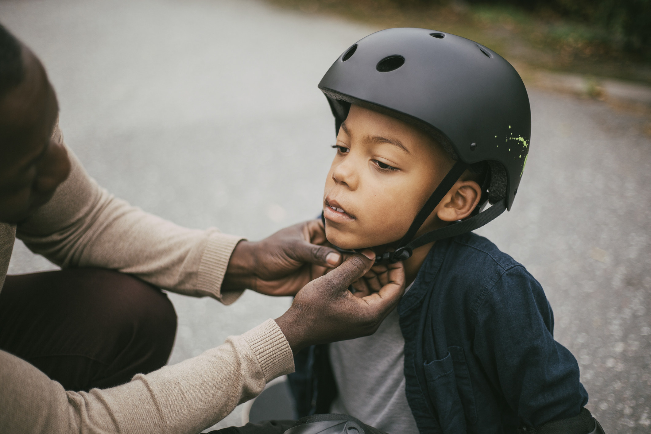A father fastening his son&#x27;s helmet