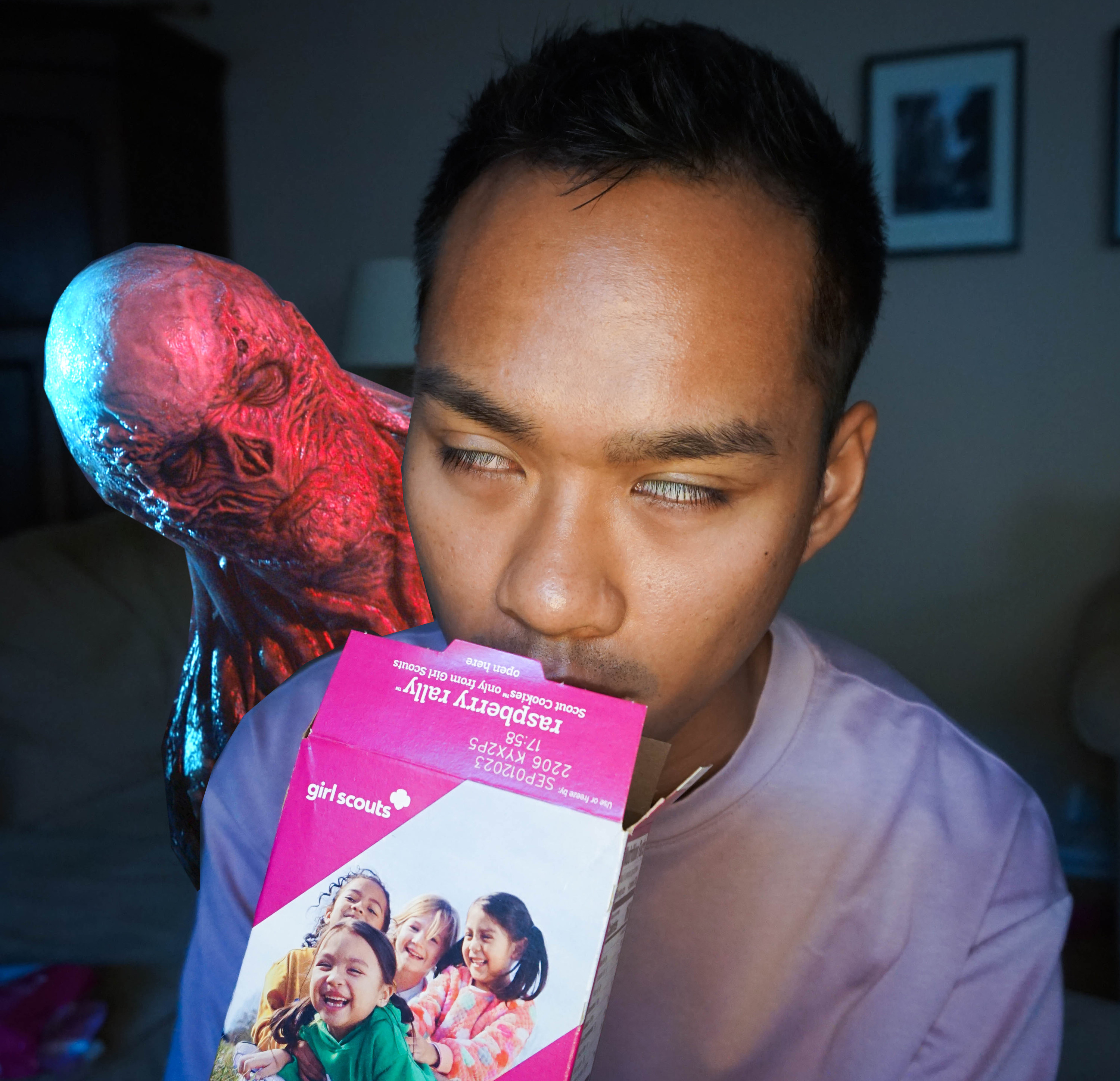 author sniffing an open box of raspberry rally girl scout cookies and rolling his eyes back with happiness with vecna from &quot;stanger things 4&quot; lurking behind him