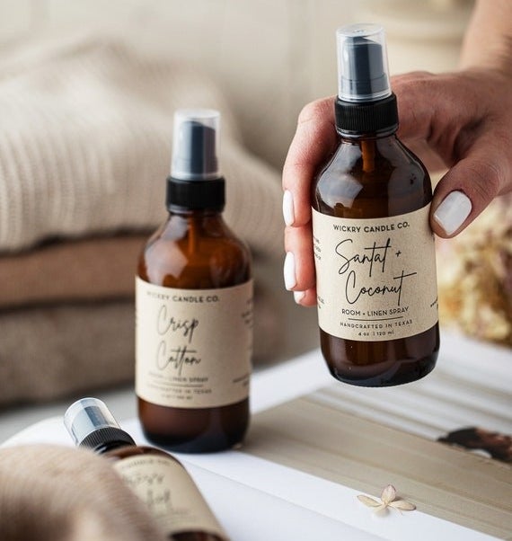 a model hand holding a spray bottle with a label that reading &quot;Santal + Coconut&quot;