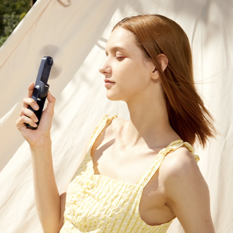 Model holding handheld fan to face