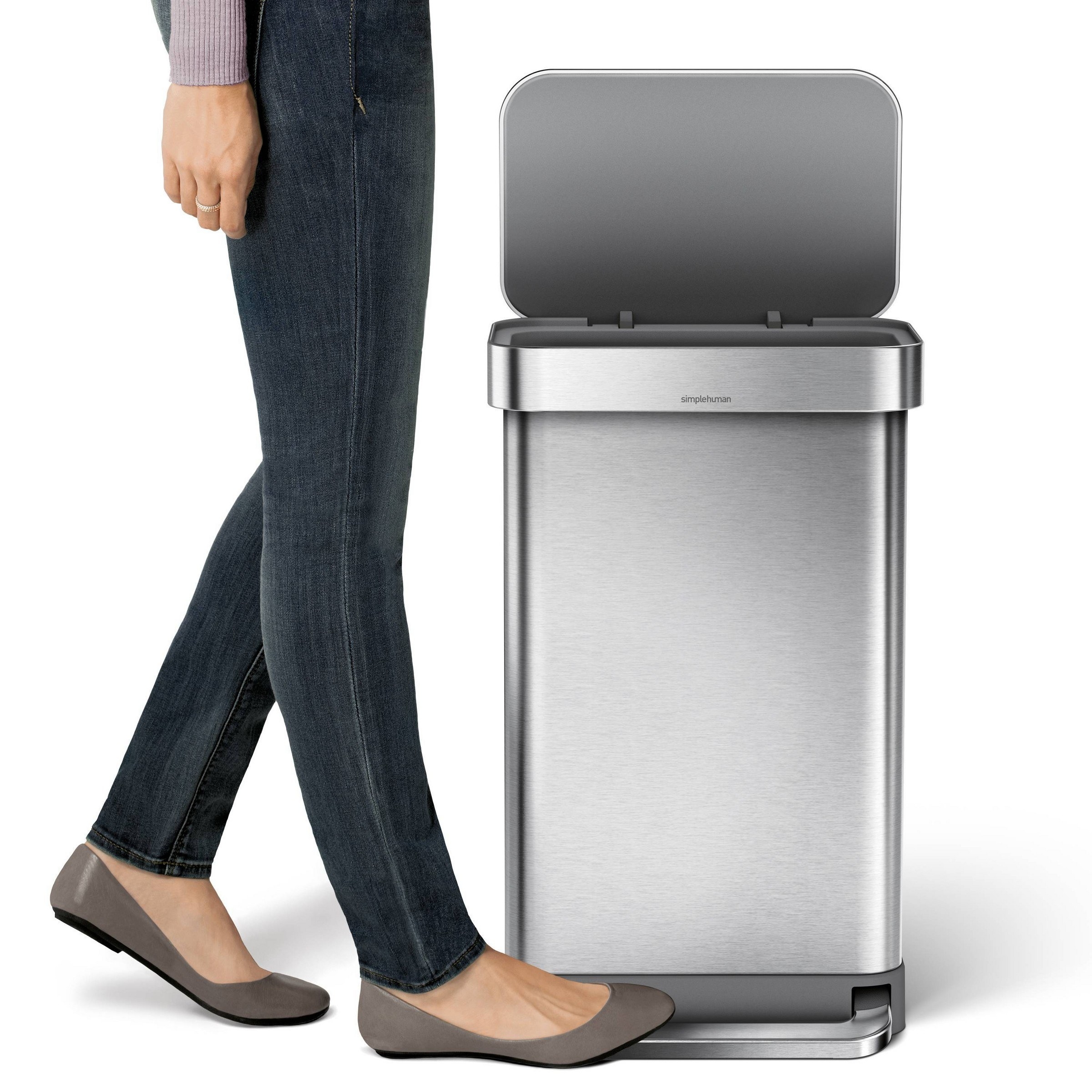 a model stepping on the trash can to open it