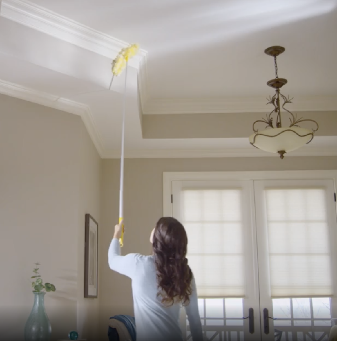 a model using the duster to clean crown molding