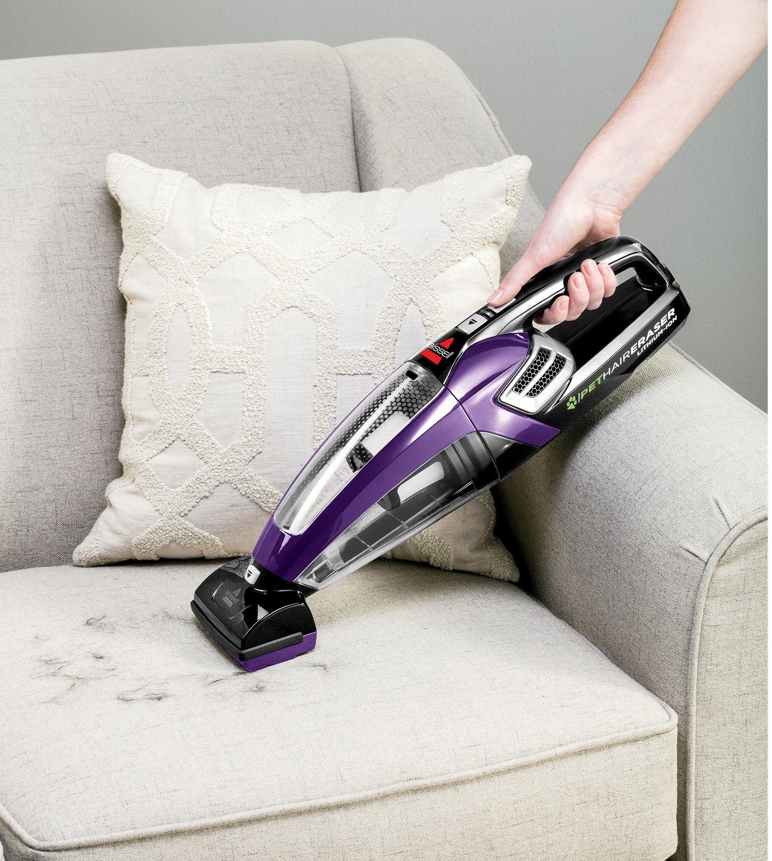 a model using it to clean pet hair off a couch