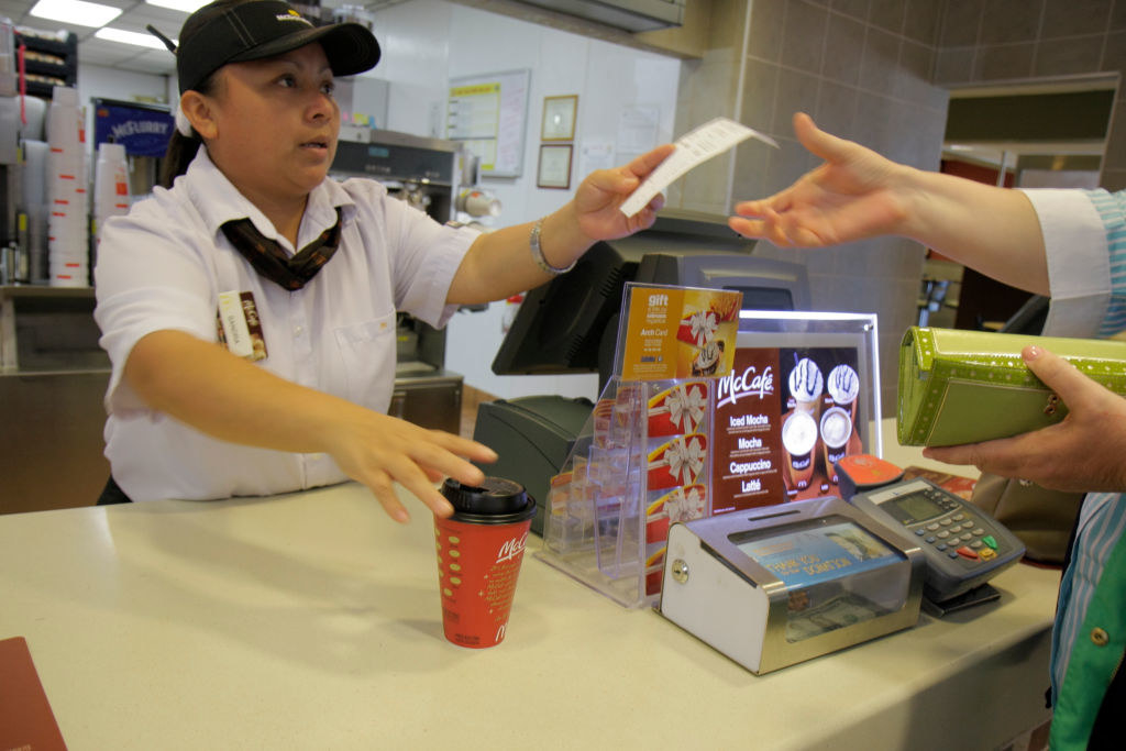 A front counter worker giving a customer their receipt