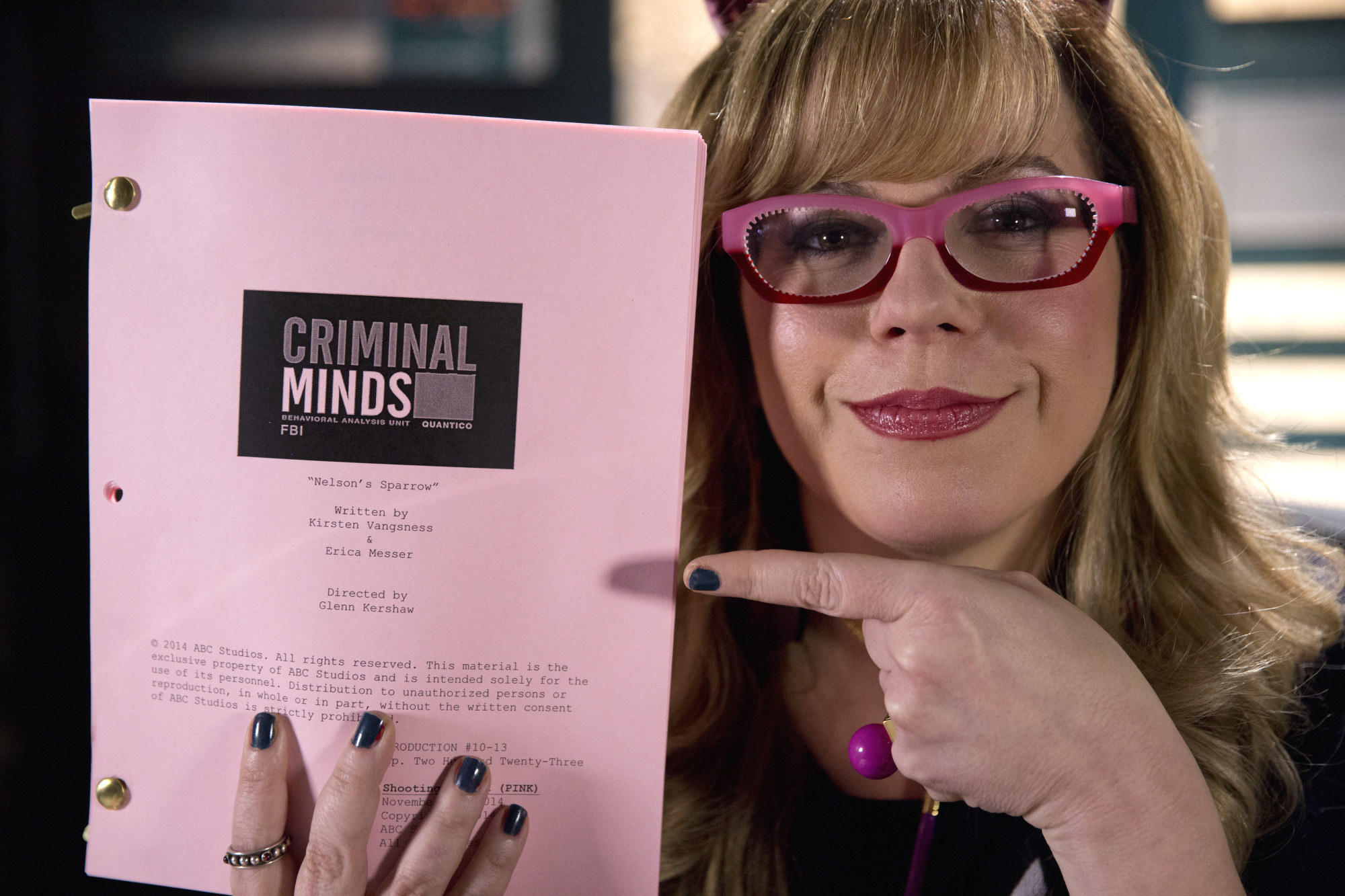 Kirsten Vangsness holding up and pointing to a Criminal Minds script
