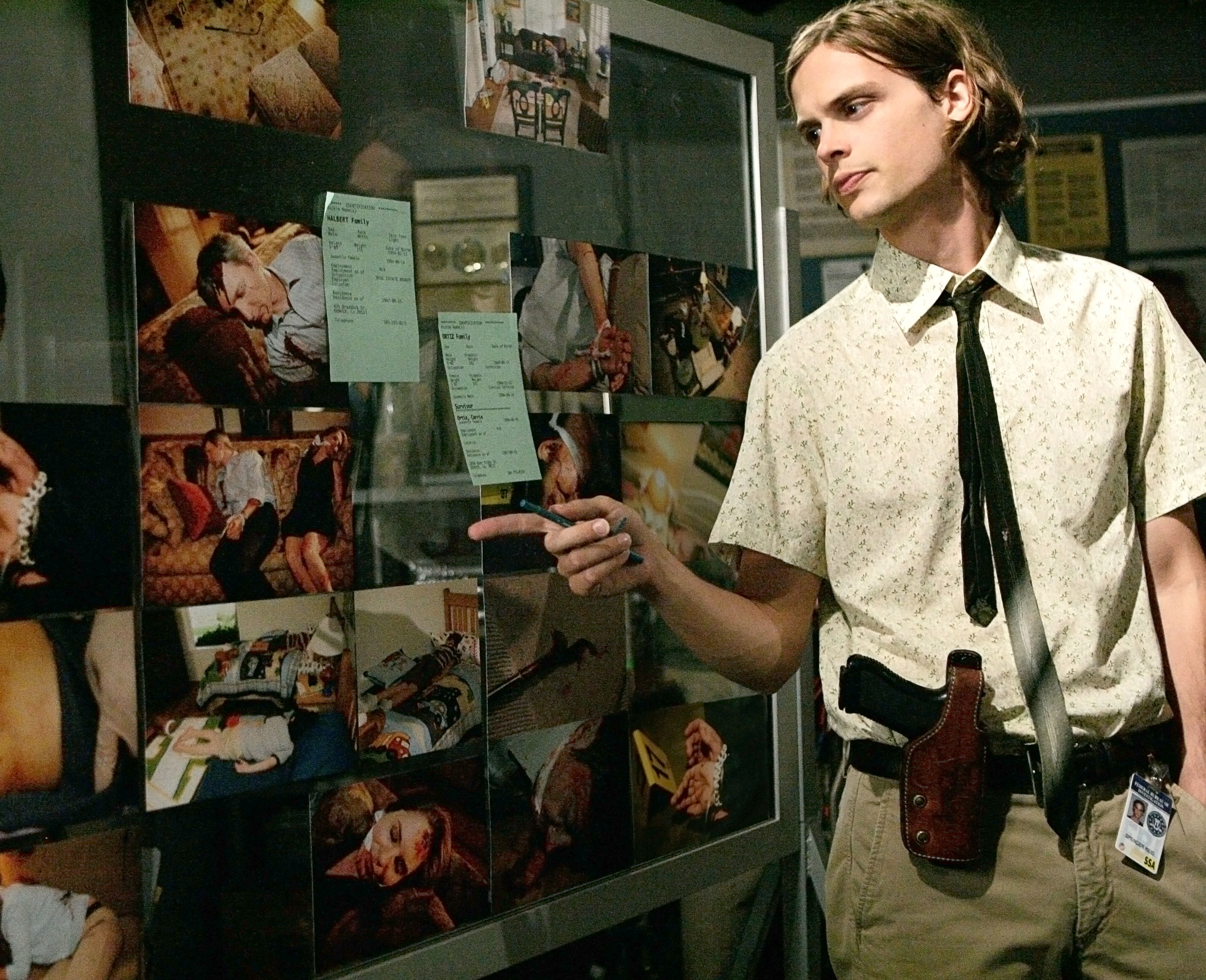 Matthew looking at a board filled with pictures during a scene of Criminal Minds