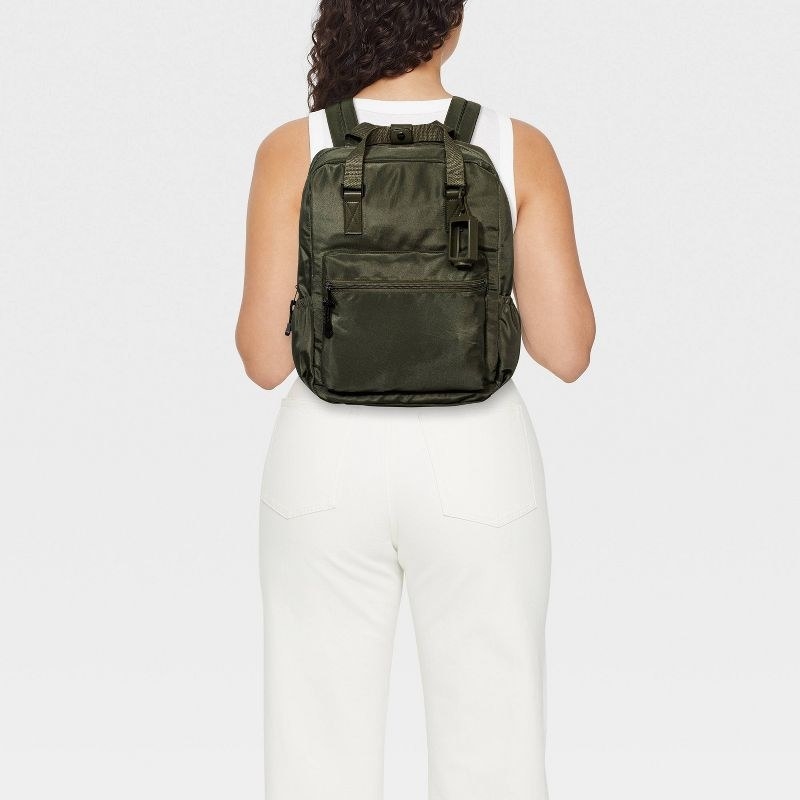 a model wearing the olive green backpack
