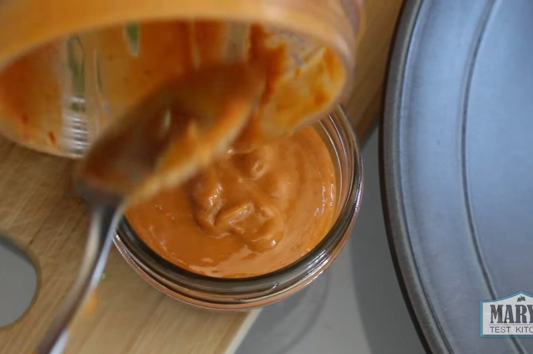 spicy peanut sauce being dolloped into a jar