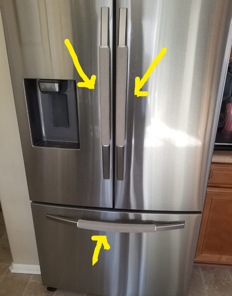 A three door stainless steel fridge with all the handles covered by gray padding 