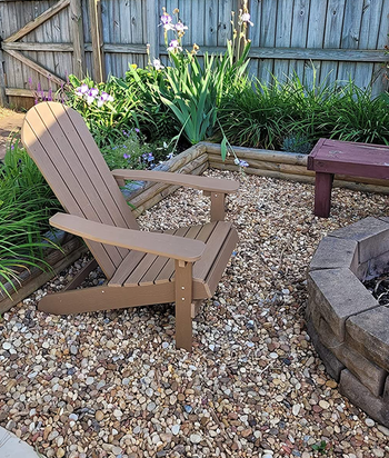 a reviewer's brown adirondack chair by a fire pit