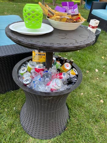 a tall table-cooler combo stuffed with iced drinks and holding snacks on top