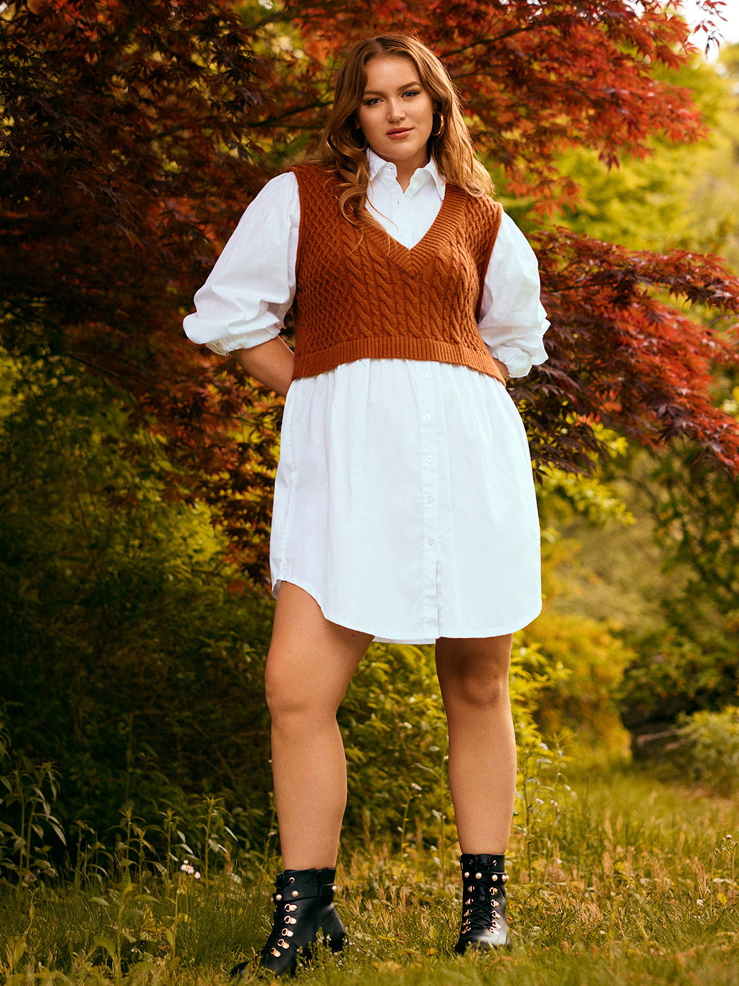 a model wearing the white shirt dress with a brown vest and black combat boots
