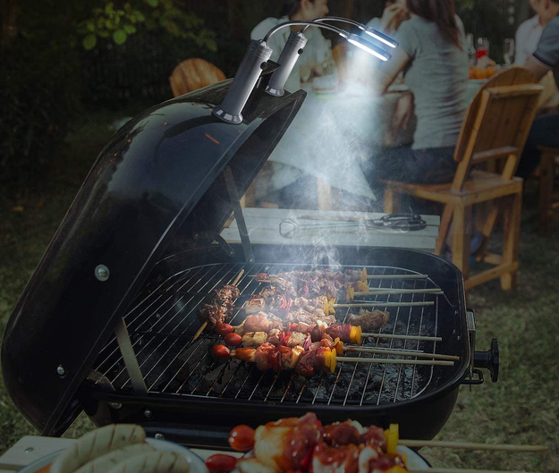 a grill with a pair of the lights attached to the top shining down on food cooking at night
