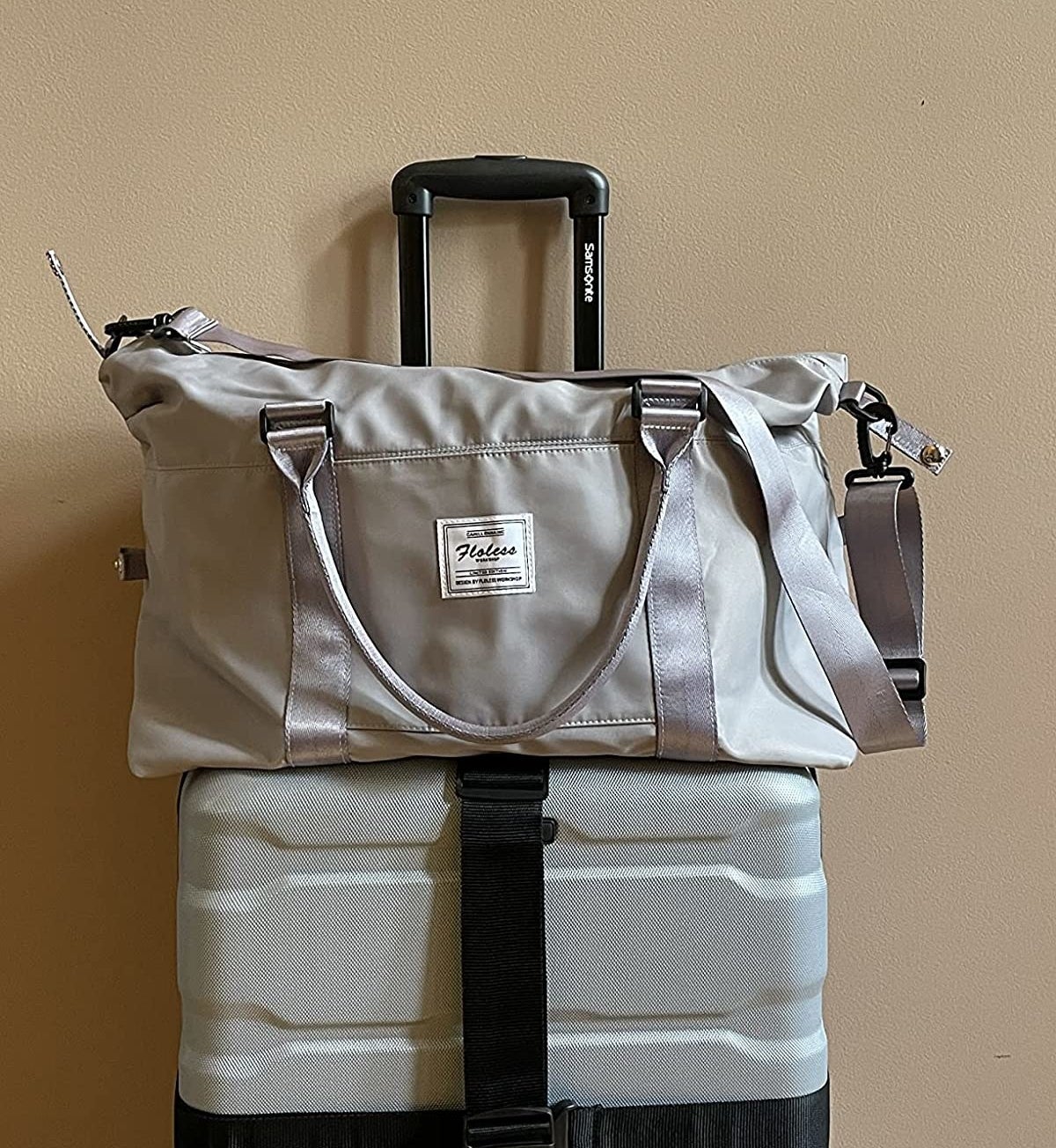 Reviewer&#x27;s photo showing the grey duffel resting on top of carry-on roller suitcase