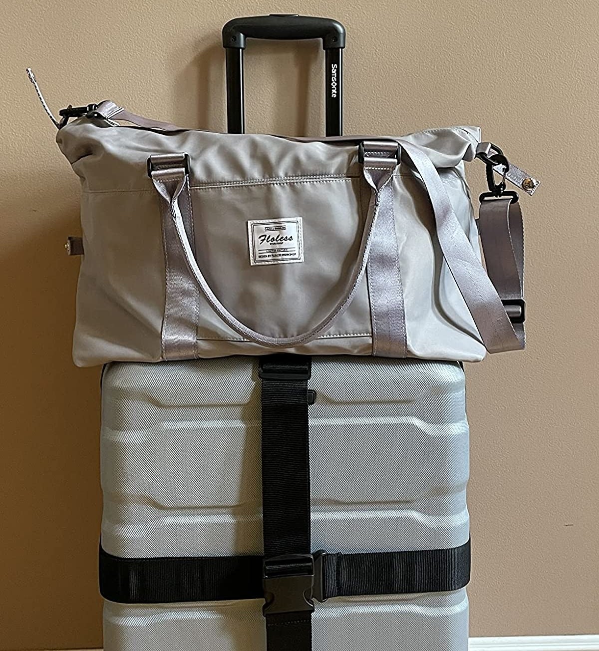 Reviewer&#x27;s photo showing the grey duffel resting on top of carry-on roller suitcase