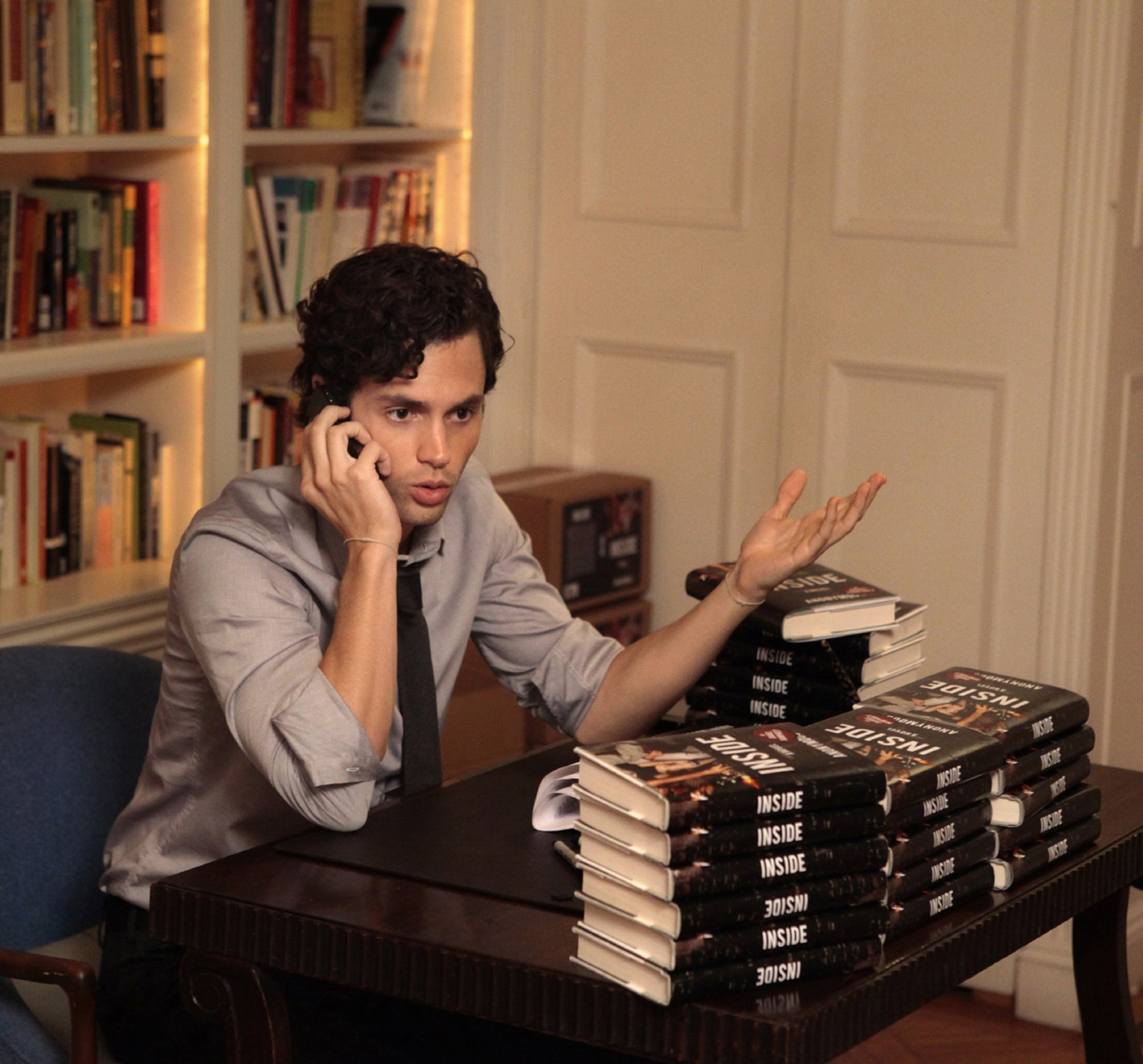 dan on the phone at a desk full of his books