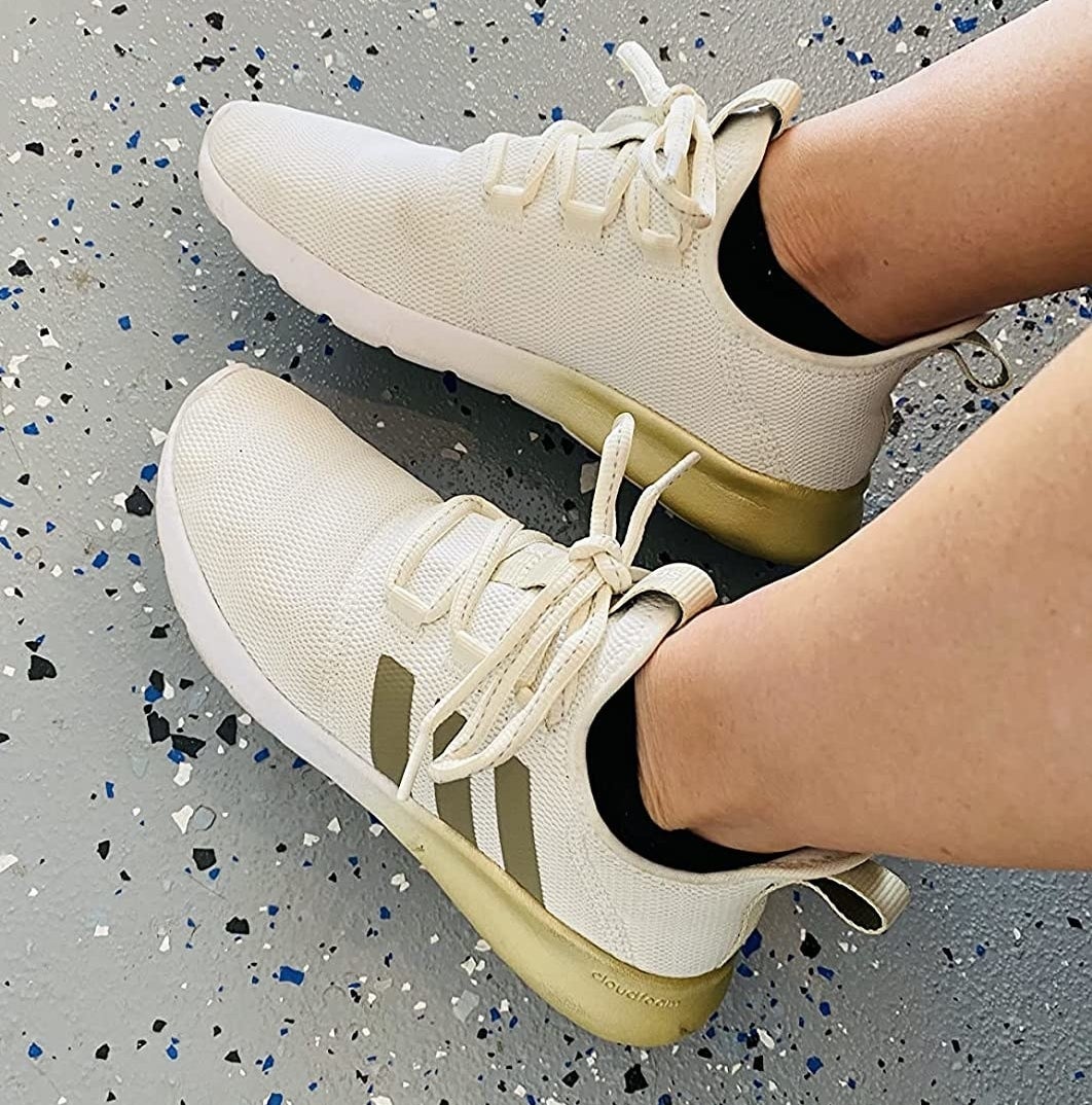 A reviewer wearing the off-white sneakers with gold detailing