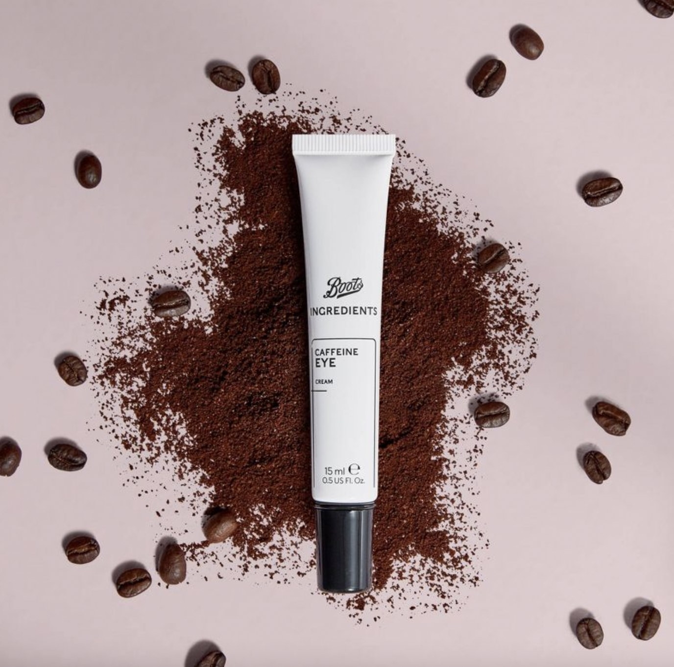 A tube of eye cream with scattered coffee beans and grounds