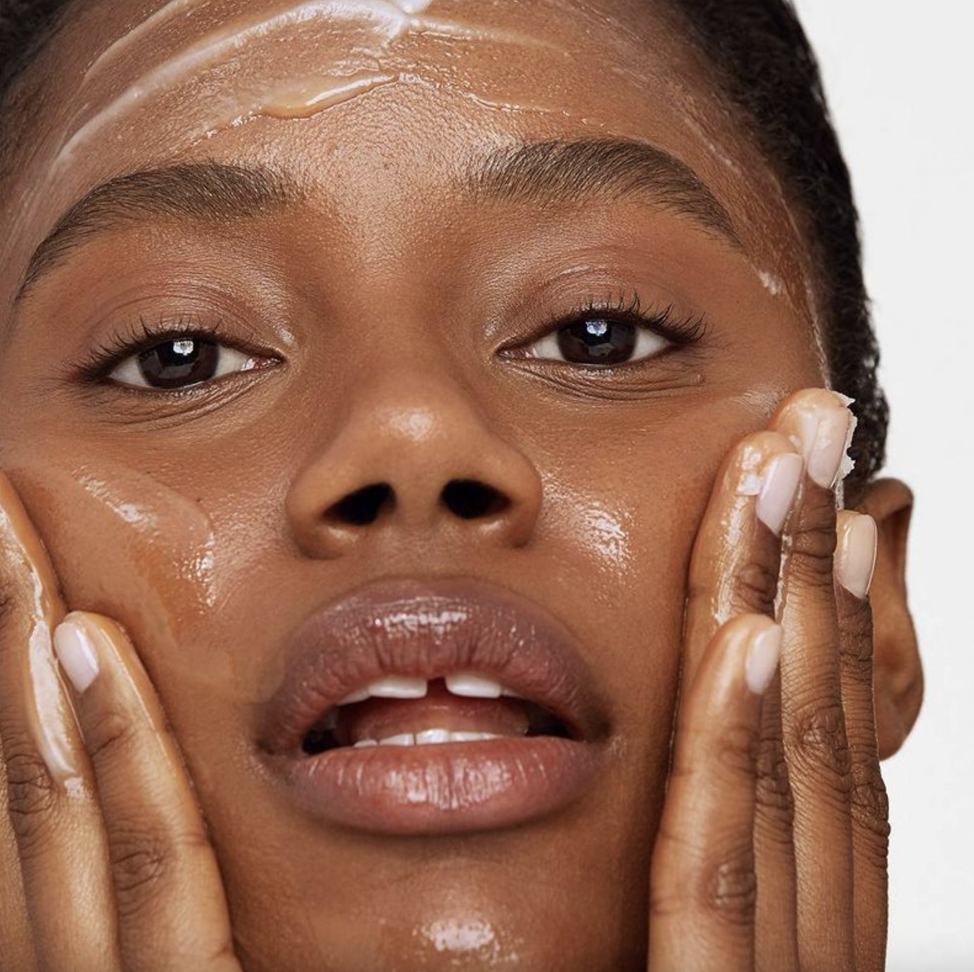 A person applying a cleansing balm to their skin