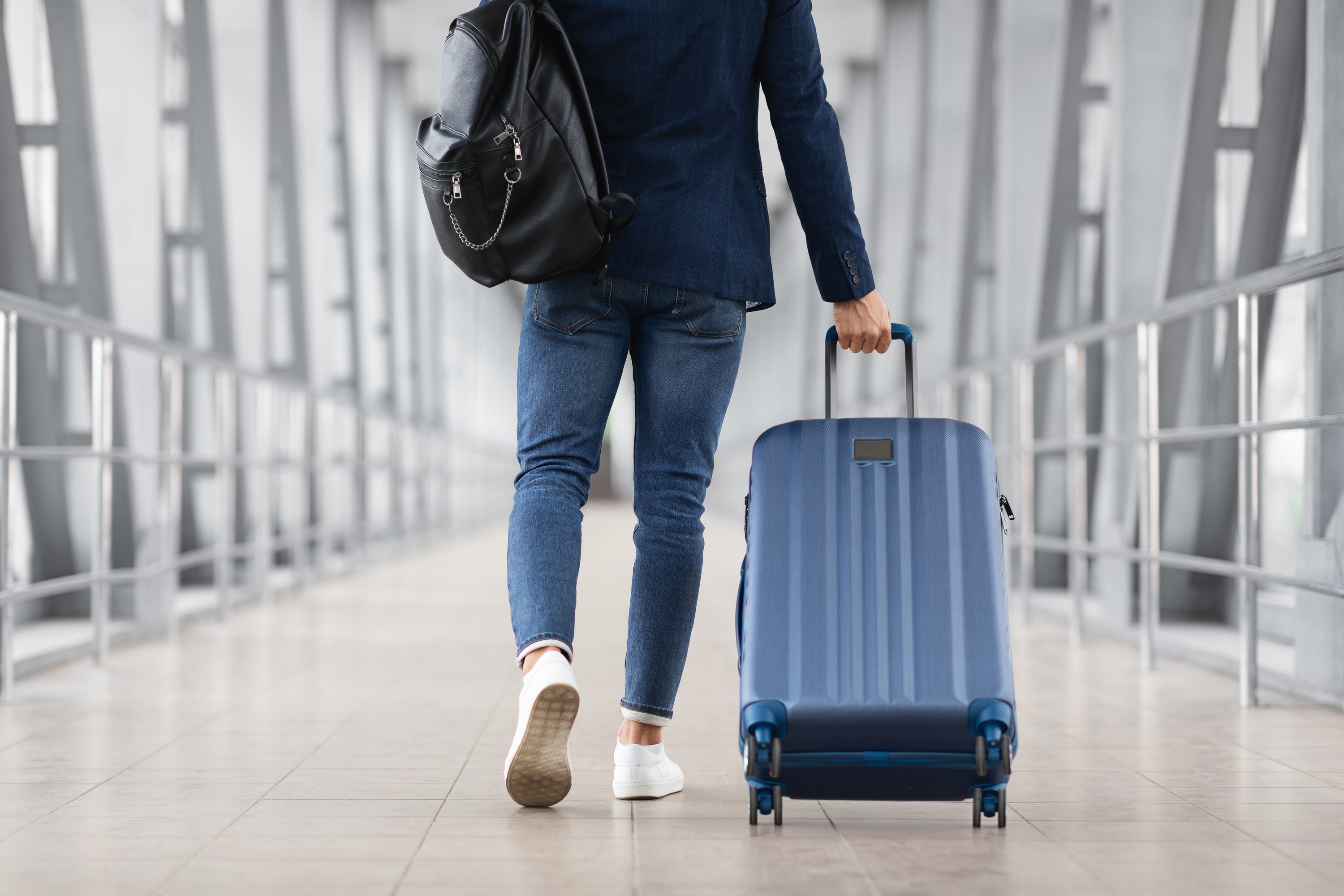 a person walking in an airport with a small suitcase