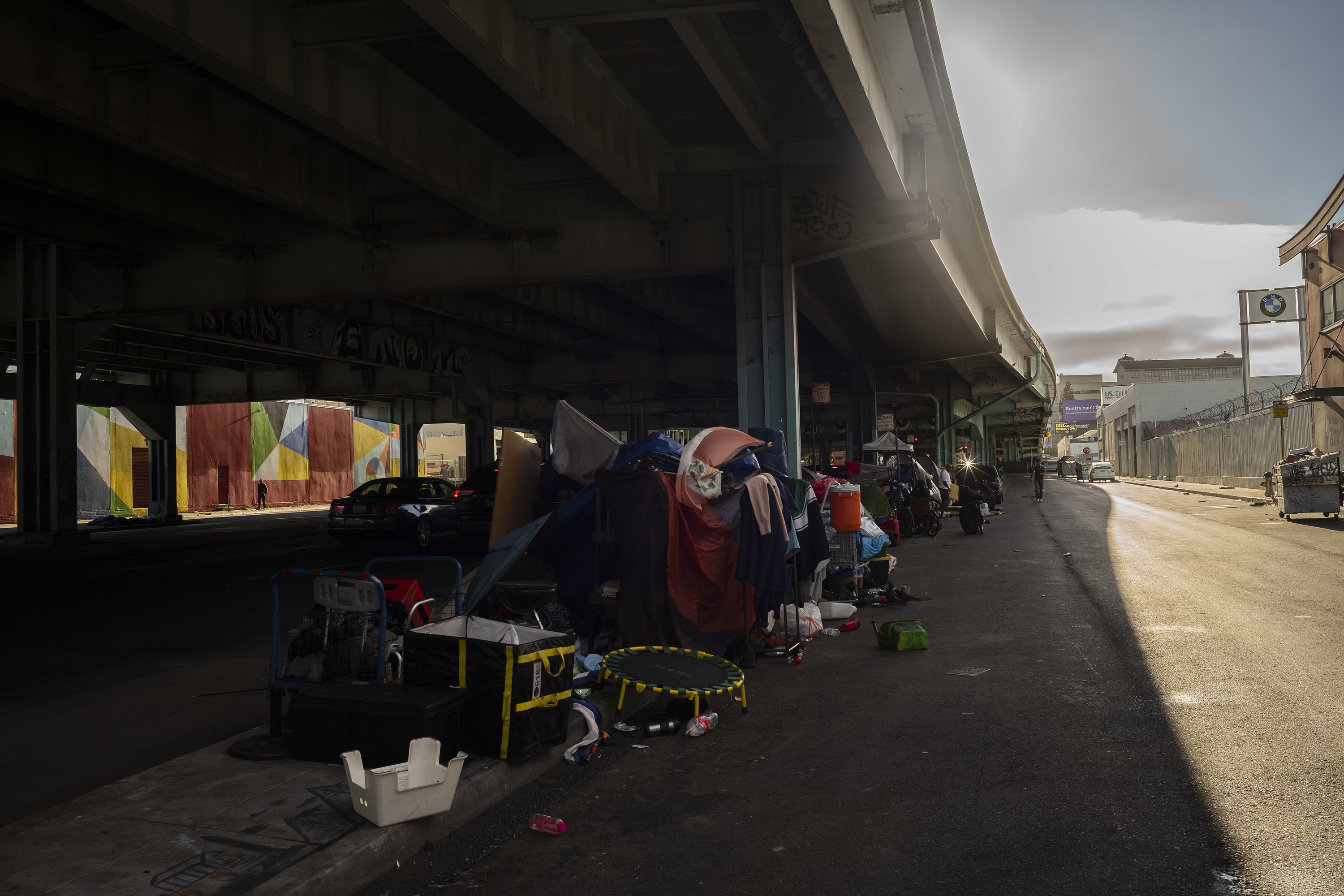 Clothes and other possessions are piled under a bridge, in a encampment for people experiencing homelessness