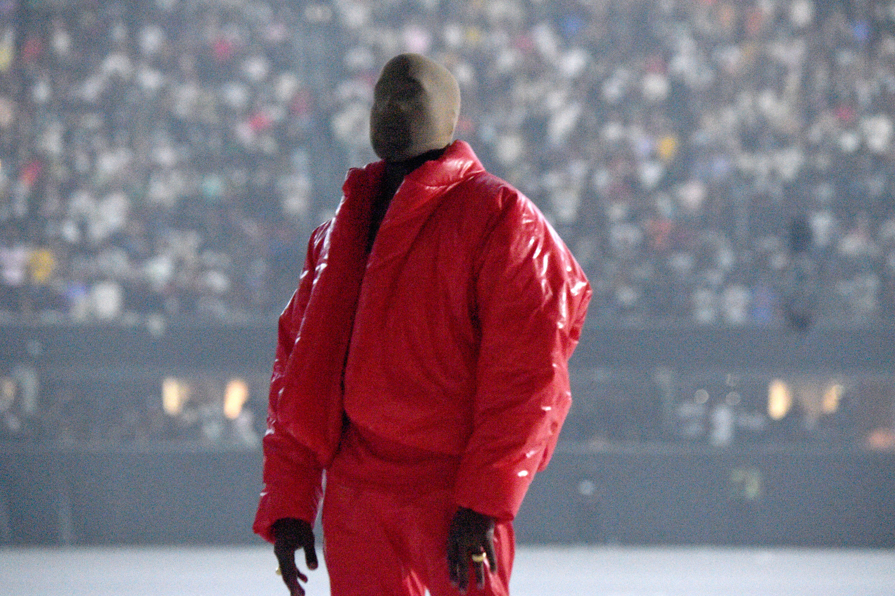 Kanye onstage in a puffer jacket and his face and head fully covered