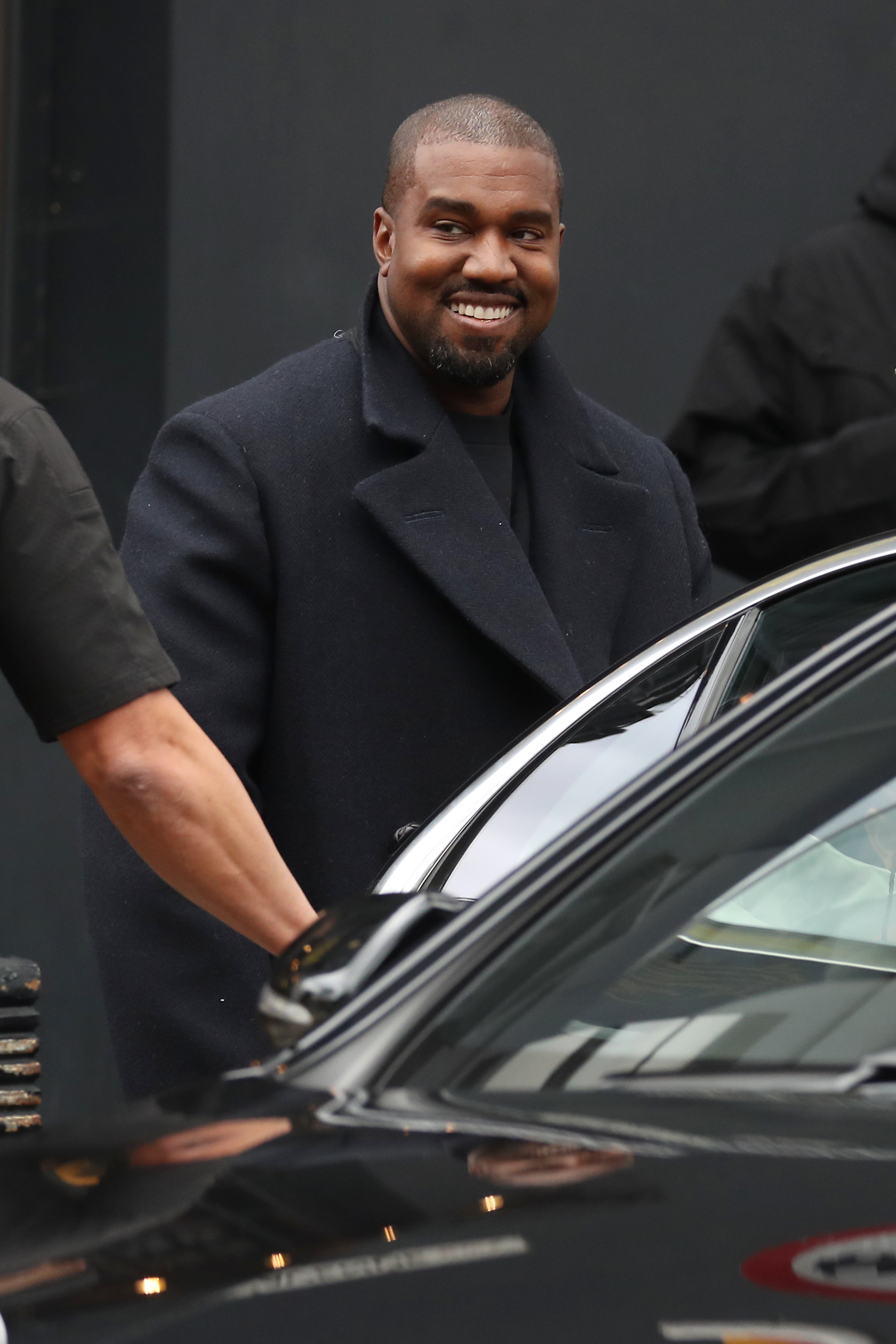 Kanye smiling and wearing a coat