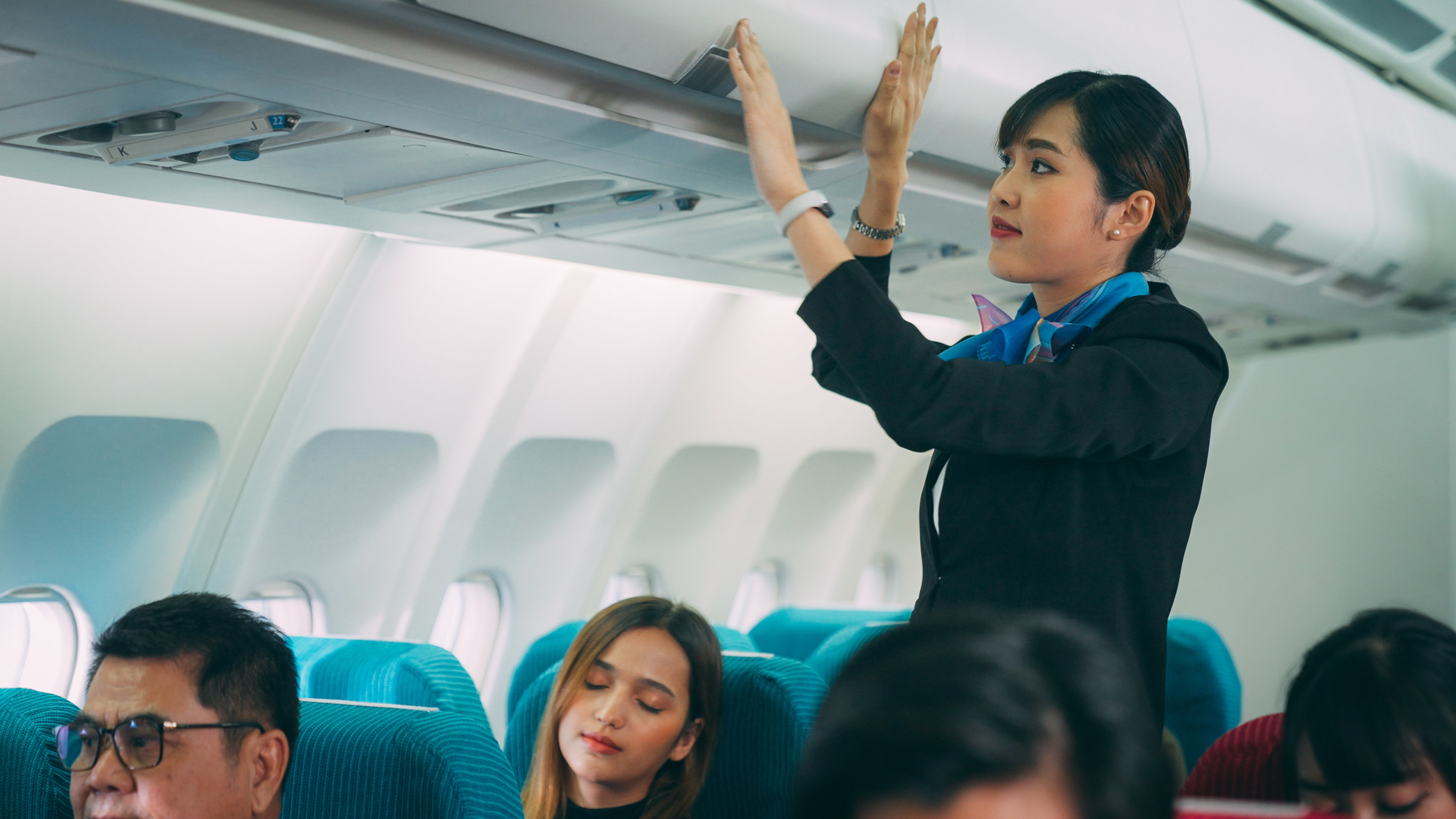 flight attendant closing the overhead bins