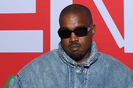 Kanye West wears a black pair of sunglasses with a blue jean jacket.