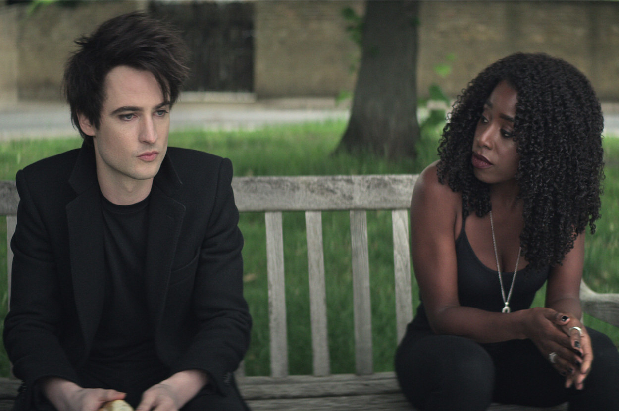 tom sturridge as the sandman sitting with kirby howell baptiste as death on a bench in a park